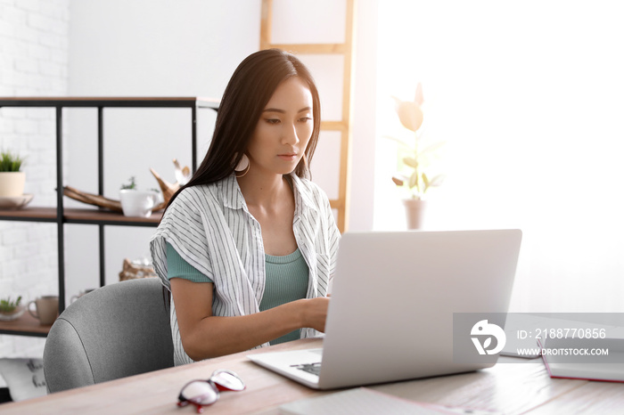 Asian blogger with laptop at table