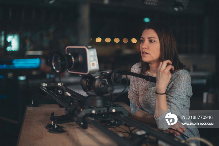 A young female director of photography at work behind a movie camera on a film set for a movie