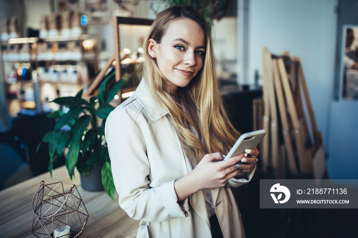 Positive young student with smartphone looking at camera