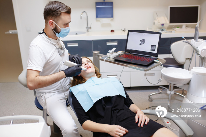 The dentist scans the patient’s teeth with a 3d scanner.