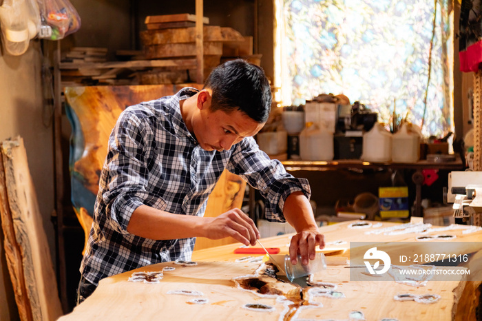 Carpenter making an epoxy wooden table