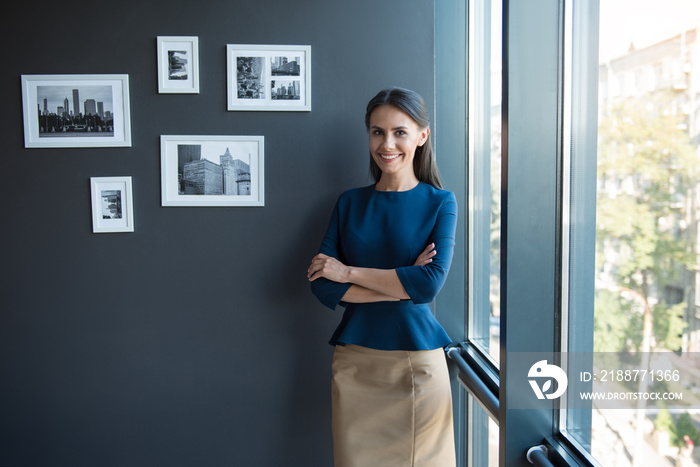 Joyful woman is posing near window