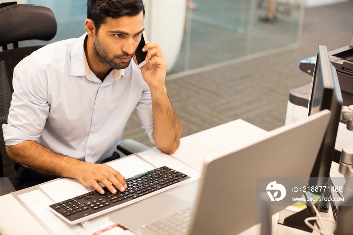 Focused businessman talking on phone while working in office