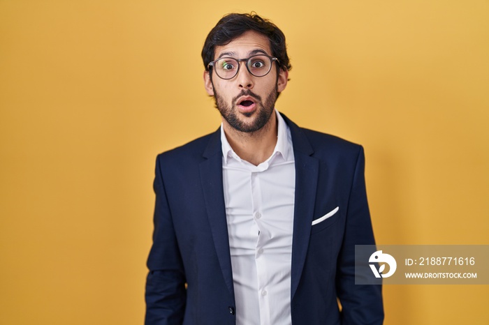 Handsome latin man standing over yellow background afraid and shocked with surprise and amazed expression, fear and excited face.