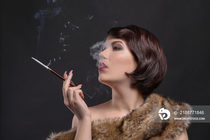 Young woman smoking with cigarette holder on dark background