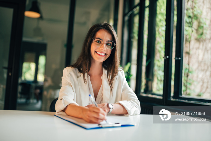 Portrait of elegant young woman completing application form.