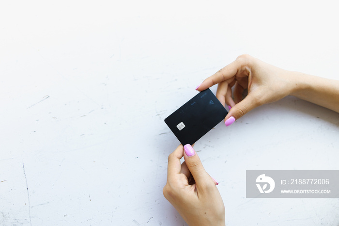 Hand with pink manicure keeping black credit card in white background.