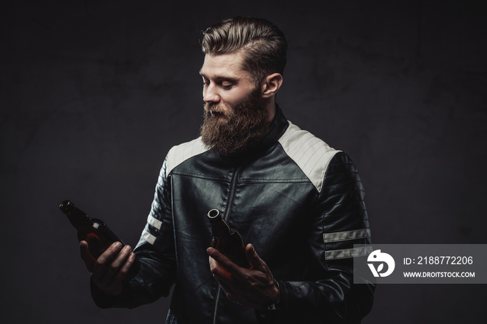 Bearded guy posing with bottles in dark background