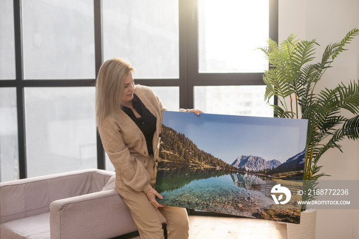 Girl hanging a photo canvas on a wall