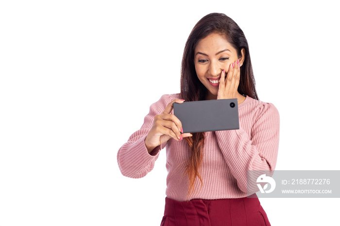 Cheerful young woman watching video in mobile phone isolated on white.