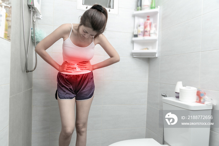 Asian Woman sitting on the toilet having pain in her stomach.