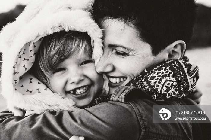 Closeup black and white group portrait of Caucasian mother and daughter baby girl hugging smiling laughing. Family on autumn fall winter season. Happy lifestyle childhood concept.