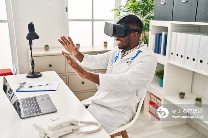 Young african american man wearing doctor uniform using virtual reality glasses at clinic