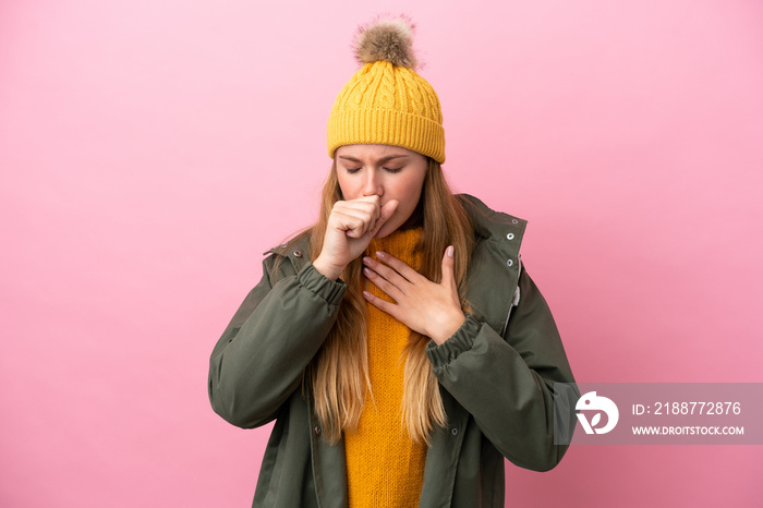 Young blonde woman wearing winter jacket isolated on pink background is suffering with cough and feeling bad