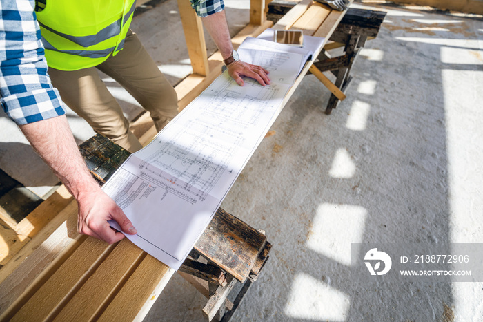 Architect or engineer on construction site looking at blueprints of building house, close up