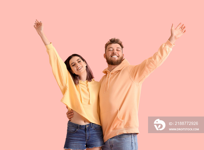 Cool happy young couple in hoodies on color background