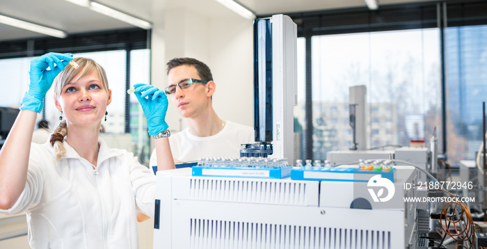 Two young researchers carrying out experiments in a lab (shallow DOF; color toned image)