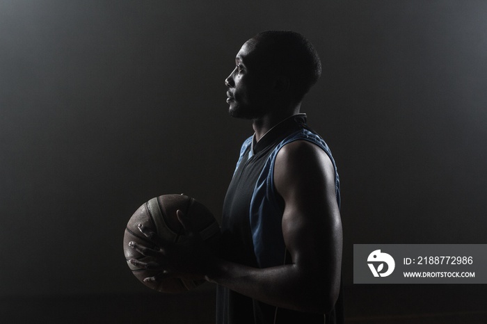 One side of a basketball player holding a basketball