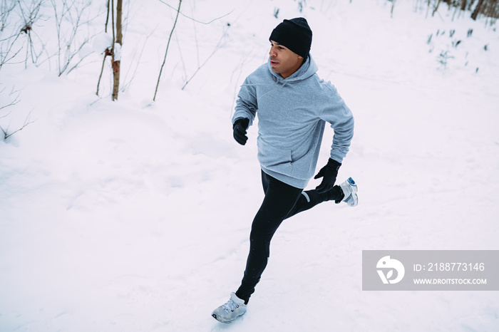 Top view of young man running in snow forest