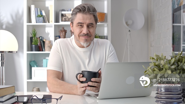 50s businessman with gray hair working from home. Man in casual sitting at desk using laptop computer, business manager online in home office.