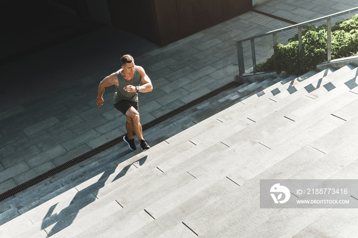 Muscular man is running upstairs by concrete staircase