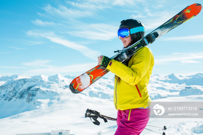 Photo of girl wearing helmet, mask with skis on her shoulder