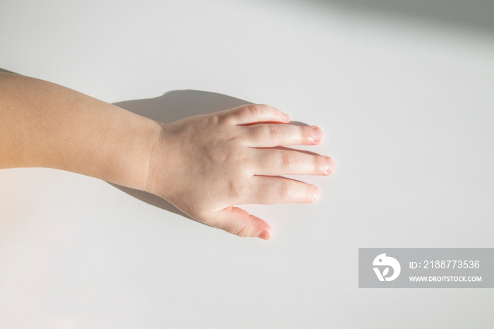 One child’s hand on a white background. Top view, flat lay.