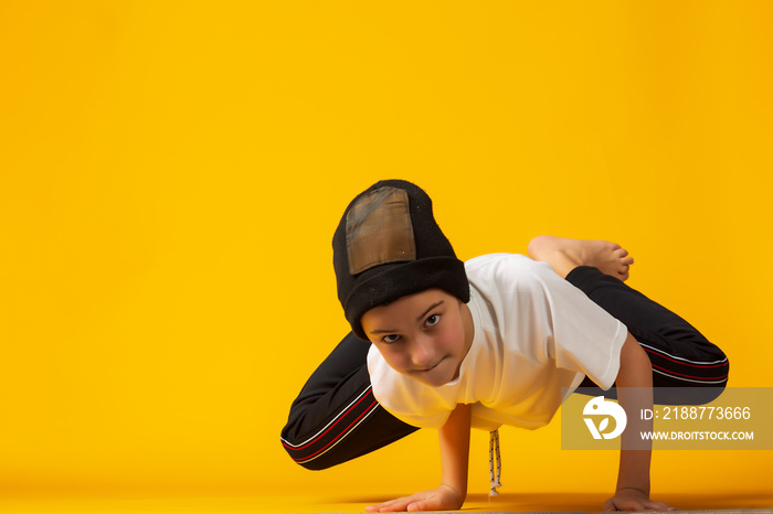 Happy little hip hop dancer - boy dancing isolated on yellow background