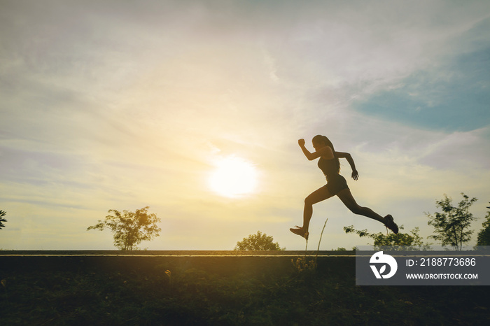 Silhouette of young woman running sprinting on road. Fit runner fitness runner during outdoor workout with sunset background.