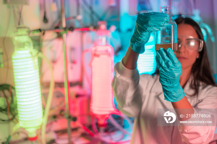 Female scientist working in a biotechnology laboratory with reactors and microalgae cultivation