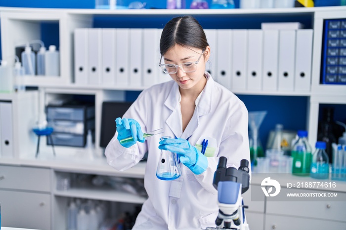 Chinese woman scientist pouring liquid on test tube at laboratory