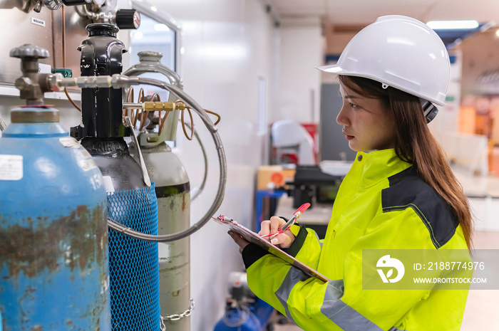 Asian engineer working at Operating hall,Thailand people wear helmet  work,He worked with diligence and patience,she checked the valve regulator at the hydrogen tank.