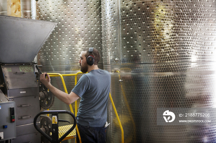 Man pulling lever by machinery in distillery