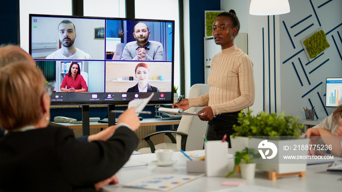 African woman discussing with remote managers on video call presenting new partners on webcam. Confident businesspeople talking to web cam streaming webcast training, doing online conference call.