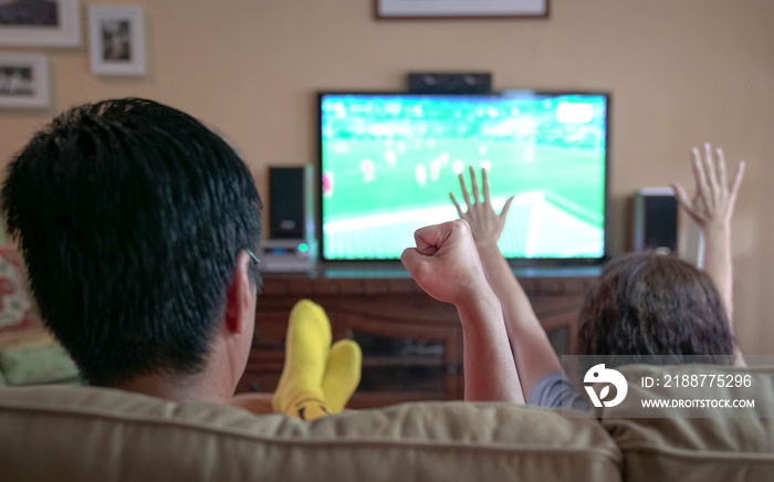 People watching sports streaming on tv, cheering with fist and hands raised. Stay at home.