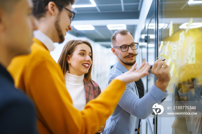 Group of business people collaborating in office discussing and planning strategy Front of glass wall marker and stickers. Education, analysis, planning management concept.