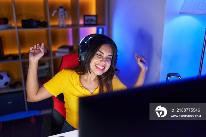 Young beautiful arab woman streamer playing video game with winner expression at gaming room