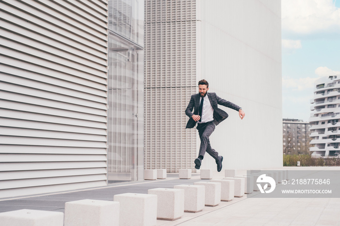 Energetic young bearded professional businessman jumping in mid-air