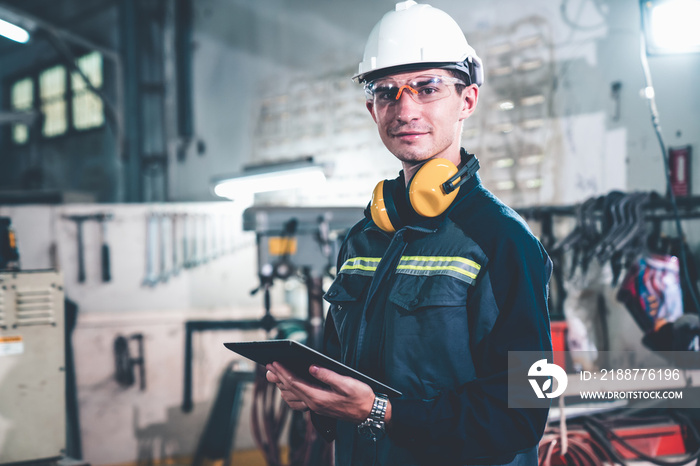 Young factory worker using adept tablet computer in a workshop building . Industrial technology and manufacturing software configuration .