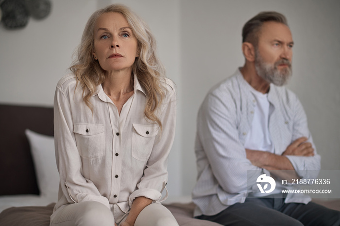 Unhappy mature couple sitting apart in silence