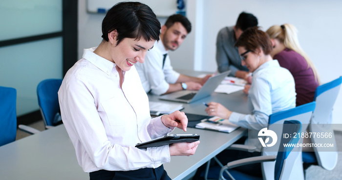 Portrait of  smiling casual businesswoman using tablet  with coworkers standing in background