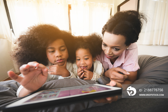 African American mum and daughter are watching the tablet relaxed in the house. Ideas about staying at home with family Teaching homework and relaxation