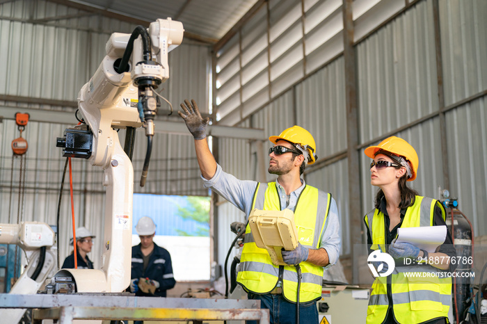 Robotics engineer working on maintenance of modern robotic arm in factory warehouse