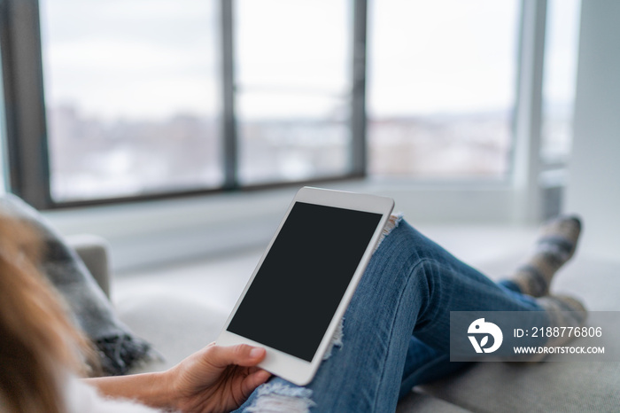 Tablet woman using pc technology device at home relaxing on sofa sitting watching video black screen or reading e-book. Tech modern lifestyle.