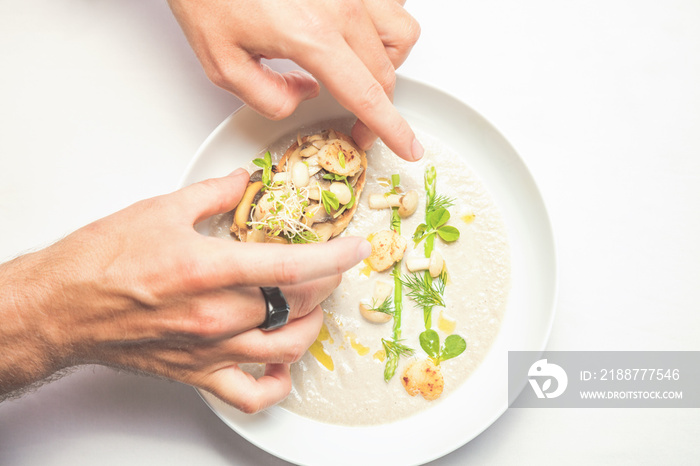 Cook chef making creme soup with herbs, mushrooms, scallops and toast bred.