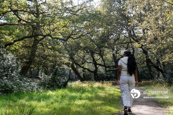 Rear view of woman walking in park on sunny day