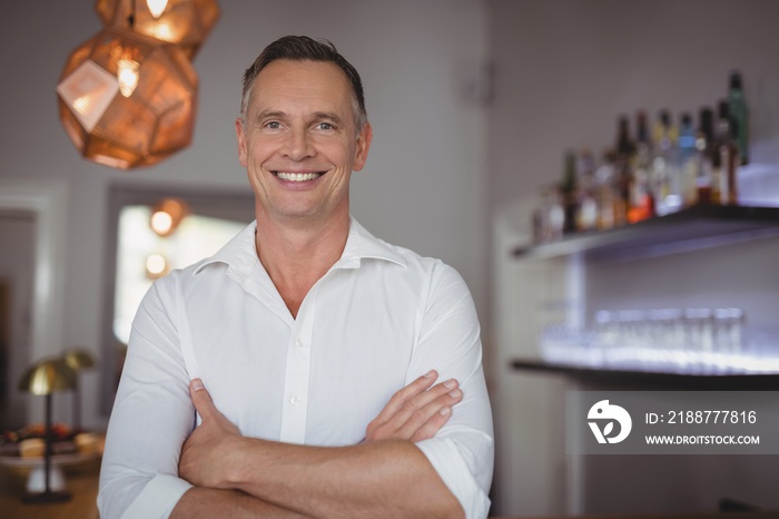 Portrait of happy man standing with arms crossed