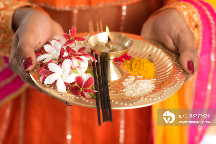 Beautiful Indian young girl holding pooja thali or performing worship on a white background