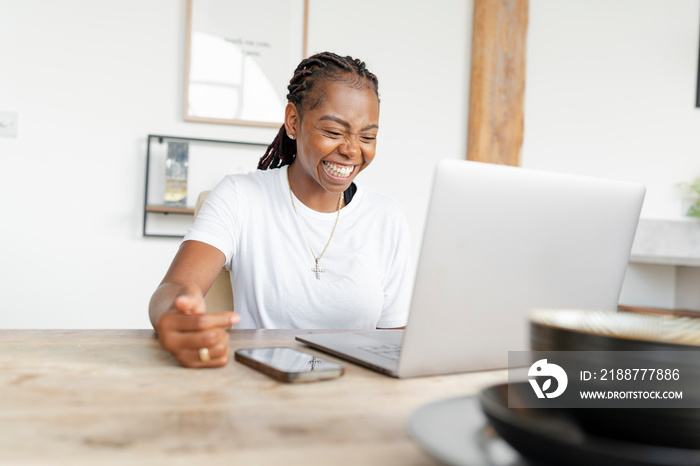 Cheerful woman working on laptop at home