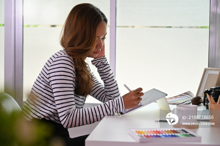 Young artist woman sketch on digital tablet on creative table.